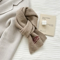 Detailed view of camel wool knit scarf with elegant red embroidery on textured fabric - Camel
