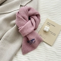 Detail of pink knitted wool scarf with blue embroidery on beige coat background - Pink