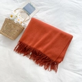 Morbida sciarpa arancione simil cashmere con frange su tessuto bianco e cesto - Rosso Ruggine