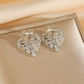 Macro shot of silver heart earrings with pavé cubic zirconia on soft satin background - Silver Stud Earrings
