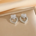 Dettaglio di orecchini a cuore in argento con zirconi bianchi su sfondo di raso - Orecchini a Bottone d'Argento / Argento