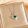 Gros plan du collier émeraude en forme de cœur sur un écrin doré avec fond satiné - Collier Coeur Vert Argenté (8458)