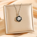 Vintage camellia necklace with black enamel and diamond petals on a golden display stand - Silver Camellia (8081)