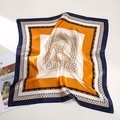 Elegant silk square scarf featuring orange and navy blue geometric patterns and soft folds - Yellow Square Grid