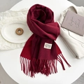 Deep red cashmere-like knitted scarf with tassels shown on white blazer - Red