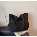 Dettaglio borsa tote in velluto nero con tasca a zip frontale e scomparti laterali aperti - Nero