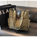 Dettaglio della borsa tote in velluto a coste oliva con tasche laterali su un divano - Verde