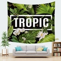 Dettaglio di un arazzo tropicale con foglie di monstera e testo TROPIC sopra un divano - Stile 14