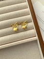 Detail van gouden strik en hart oorbellen op een beige fluwelen sieradendisplay dienblad - Gouden strik hart oorknopjes