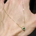 Dettaglio di un ciondolo a V dorato con gemma triangolare verde smeraldo e piccoli cristalli - Collana Grande con Zircone Triangolare