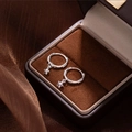 Macro detail of silver star pendant earrings on premium brown leather jewelry box - Star Earrings