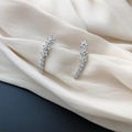 Detailed view of silver crawler earrings with sparkling star flowers on white silk background - Star Zirconia Studs
