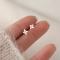 Macro shot of silver four-pointed star stud earrings with micro-inlaid cubic zirconia - Tiny Cross Star Studs