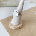 Macro view of a polished silver oval disc ring displayed on a natural linen cone stand - Adjustable Open / Smooth Round Style
