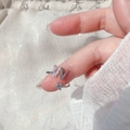 Close-up of adjustable silver letter W ring with cubic zirconia paving on silk fabric - Letter W