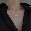 Close-up of twisted silver necklace with zircon pendant worn by a model on black shirt - White Gold