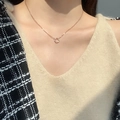 Elegante roségouden ketting met gedraaide ringhanger op model met een gebreide trui - Roségoud