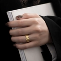 Close-up of golden irregular textured ring worn by a model against a black suit - Wide Wave Lava Texture Style (R1038)
