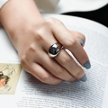 Close-up of a minimalist silver wide domed ring on a finger with a magazine backdrop - Wide Cabochon Arc Polishing Style (R1034)