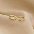 Vista macro di orecchini huggie a V dorati con pavé di zirconi trasparenti - Fibbia per Orecchio a Forma di V con Zirconi