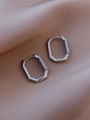 Silberne achteckige Creolen mit Mikro-Zirkonia auf seidigem Hintergrund im Detail - Weißgold