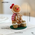 Brown gingerbread man doll ornament with red bow and striped scarf on green base - Gingerbread Man With Red Bow