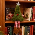 Plush Christmas tree ornament with long striped legs on a festive wooden bookshelf - Green