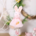 Roze pluche konijntje met worteldetail hangend aan een decoratieve witte tak - Roze Konijntje