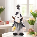 Cow print gnome with brown antlers holding a sunflower in a cozy home setting - Style With Sunflower (W-QT69)