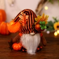 Fall gnome plush with striped hat and maple leaf on a warm rustic wooden background - Holding Pumpkin Style