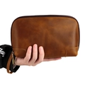 Close-up of vintage brown leather clutch bag with bronze hardware and wrist strap - Brown