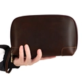 Macro shot of dark brown vintage leather pouch with zipper and orange stitching detail - Coffee