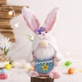 Rosa Osterwichtel-Plüsch mit Hasenohren und weißem Bart mit einer blauen Blumentasche - Eierschale Haltender Stil