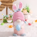 Gnomo di Pasqua rosa e blu con orecchie da coniglio che tiene un uovo di Pasqua blu - Rosa
