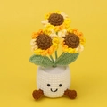 Detail einer handgefertigten Häkel-Sonnenblume im süßen lächelnden Topf auf gelbem Grund - 3-Kopf Farbverlauf Sonnenblume (Weißer Topf mit Füßen)