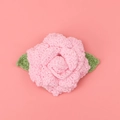 Detailansicht der handgehäkelten Rose mit rosa Blütenblättern und grünen Blättern für DIY - Hellrosa