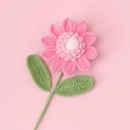 Detailed view of handmade crochet pink sunflower with soft yarn texture and green leaves - Pink