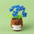 Close-up of blue crochet puff flower in a smiling pot with a small white gift card - Blue Forget-me-not