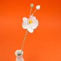 Detail einer handgehäkelten weißen Orchidee mit rosa Blütenblättern in weißer Vase - Weiß
