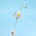 Detail einer handgehäkelten hellblauen Orchidee mit Knospen in weißer Keramikvase - Blau
