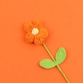 Dettaglio di fiore a sbuffo fatto a mano all'uncinetto con petali arancioni e stelo verde - Arancione