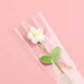 Detail of handmade crocheted flower in LOVE transparent gift packaging on pink background - White