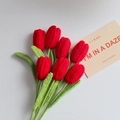 Detailed macro view of 7 red hand-knitted crochet tulips with green yarn stems and leaves - Closed Tulip Single Finished Product / Red
