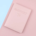 Pink faux leather passport cover with embossed logo on a dual-tone pastel background - Pink