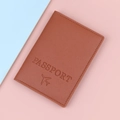 Brown leather passport cover with embossed airplane icon on bicolored background - Brown