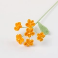 Nahaufnahme handgehäkelter orangefarbener Blumen mit grünen Blättern und Textur - Orange