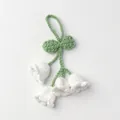 Detailed macro view of handmade crochet lily of the valley flowers with green leaves - White