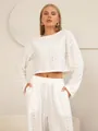 Detail van witte tweedelige eyelet-borduurset met korte top met lange mouwen en wijde broek - S / Wit