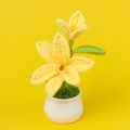 Close-up of handmade crochet yellow lily potted plant with white ceramic pot details - Yellow