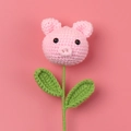 Détail d'une fleur de cochon rose faite main au crochet avec texture tricotée et tige verte - Style Petit Cochon Rose
